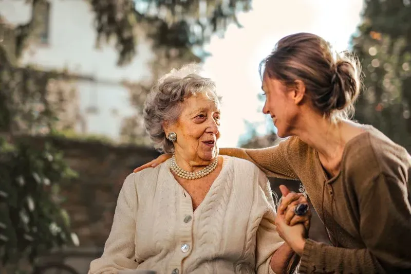 senior woman being embraced by adult daughter
