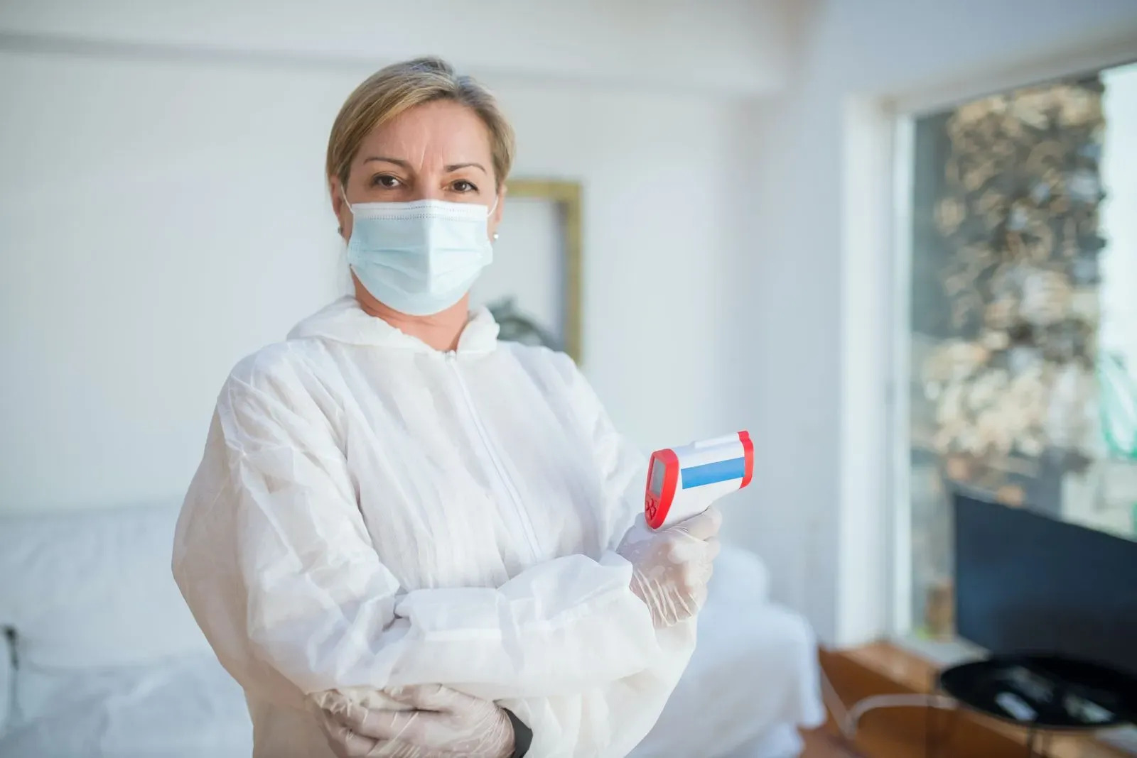 nurse in hazmat and mask with temperature gun