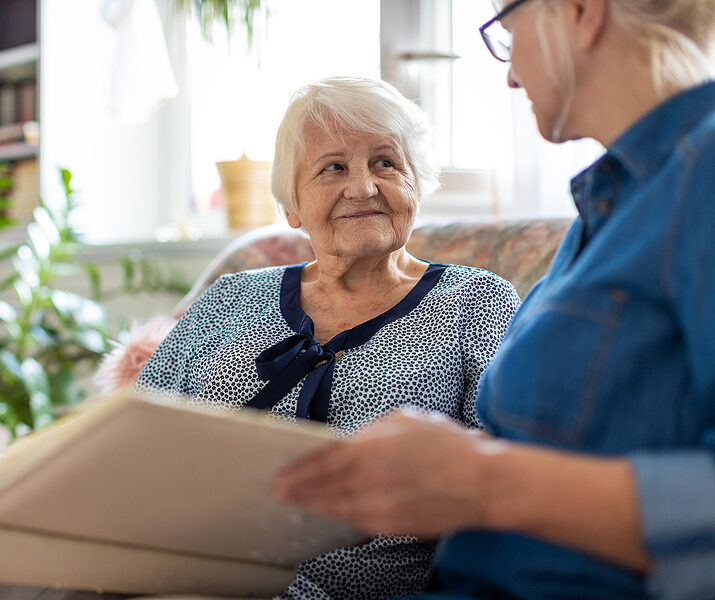 Senior woman and her adult daughter looking at photo album together